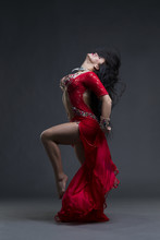 Young Beautiful Exotic Eastern Women Performs Belly Dance In Ethnic Red Dress On Gray Background