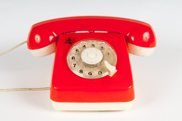 Retro orange telephone with rotary dial on white