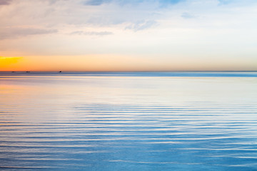 Still blue sea water under colorful sky