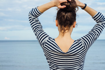 Wall Mural - Woman in a striped shirt looking at the sea