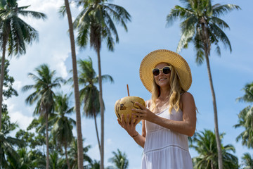 Poster - Young woman with fresh coconut in his hand walking through the jungle
