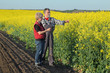© sima - Farmer and agronomist examine blossoming rapeseed field