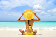 Summer Beach Vacation Carefree Happy Woman Relaxing Enjoying Sun Holiday In Tropical Destination. Perfect Paradise Happiness. Back View Of Bikini Girl Holding Yellow Fashion Hat On Caribbean Holiday.