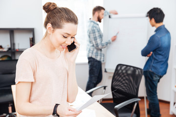 Canvas Print - Cheerful businesswoman talking on mobile phone in office