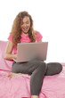 © vladimirfloyd - happy young woman sitting on a bed with a laptop on the legs