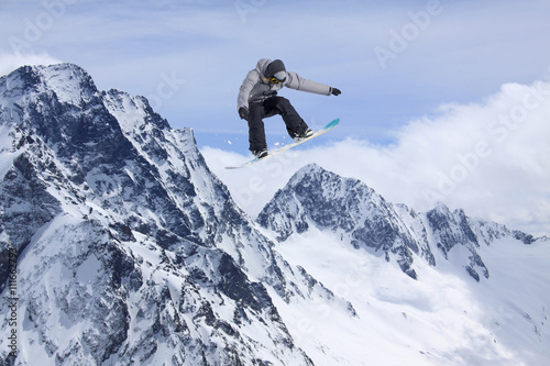 Cuadros en Lienzo Corredor de snowboard que salta sobre las montañas