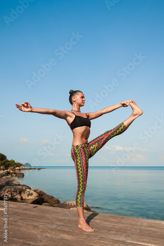 Poster Woman doing yoga in the morning at the sea.