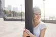 © anderpe - Beautiful young woman hidden behind a black lamp on harbor. She is looking at camera, laughing and hugging a lamp. Sunset gives very nice atmosphere