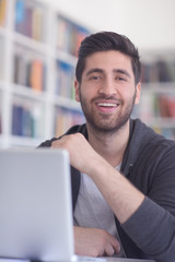 Canvas Print - student in school library using laptop for research