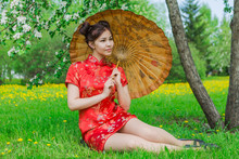 Beautiful Asian Girl In Traditional Chinese Red Dress With Bamboo Umbrella.
