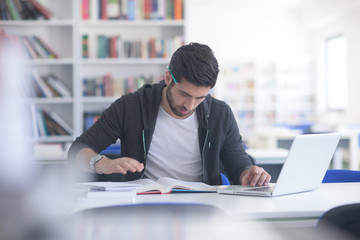 Canvas Print - student in school library using laptop for research