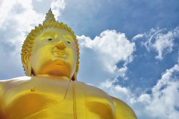 Giant golden buddha statue on cloudy sky