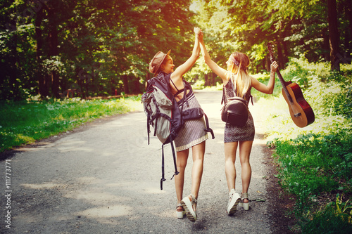Fotografie, Obraz Two woman traveler walking along the road through woods