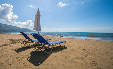 Wall Mural - Empty lounge chairs with sun umbrella on sandy beach