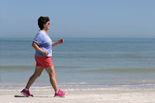 Senior Woman Power Walking On A Gulf Coast Beach.