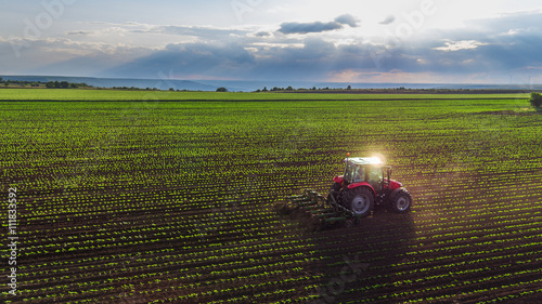 Fotografía Tractor cultivating field at spring