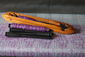 Wall Mural - Weaving shuttle with thread on the lilac warp