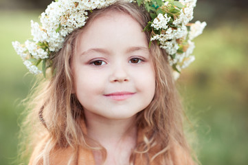 Poster - Cute kid girl 4-5 year old with flowers in hairstyle outdoors. Looking at camera. Childhood.