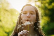 Teen Girl Blowing Dandelion To The Camera, Focus On Girl