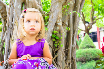 little girl in a tropical garden. bonsai tree