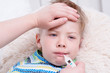 © Ermolaev Alexandr - Sick kid with high fever laying in bed and mother taking temperature