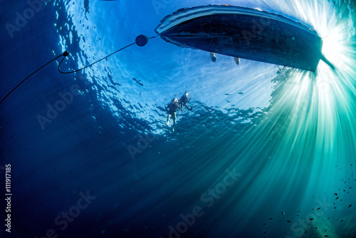 Fotomural boat ship from underwater blue ocean with sun rays