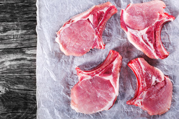 Poster - Raw fresh pork chops on a white parchment paper, top view