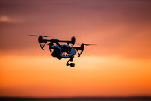 Quadrocopter Drone With Remote Control. Dark Silhouette Against Colorfull Sunset. Soft Focus. Toned Image