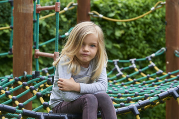 Portrait of Happy little blond girl playing on a rope web playground outdoor