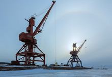 Ships Cargo Cranes On Shore Of Lake Baikal In Winter At Sunset.