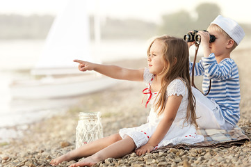 Boy with a girl sitting on the beach and looking into the distance