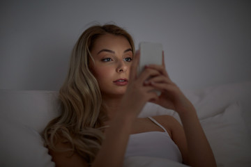 Poster - young woman with smartphone in bed at home bedroom