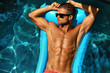 Man Body In Summer. Male In Pool. Beautiful Sexy Model In Fashion Sunglasses Tanning In Swimming Pool Water At Resort. Fit Guy With Healthy Sun Tan Skin Relaxing On Holidays Vacation. Summertime Relax