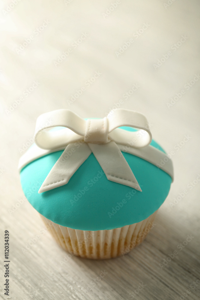 Tasty cupcake with bow on light background