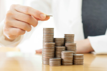 Businesswoman put coins to stack of coins