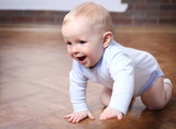 Fototapeta  - Crawling baby on the wooden floor in the room