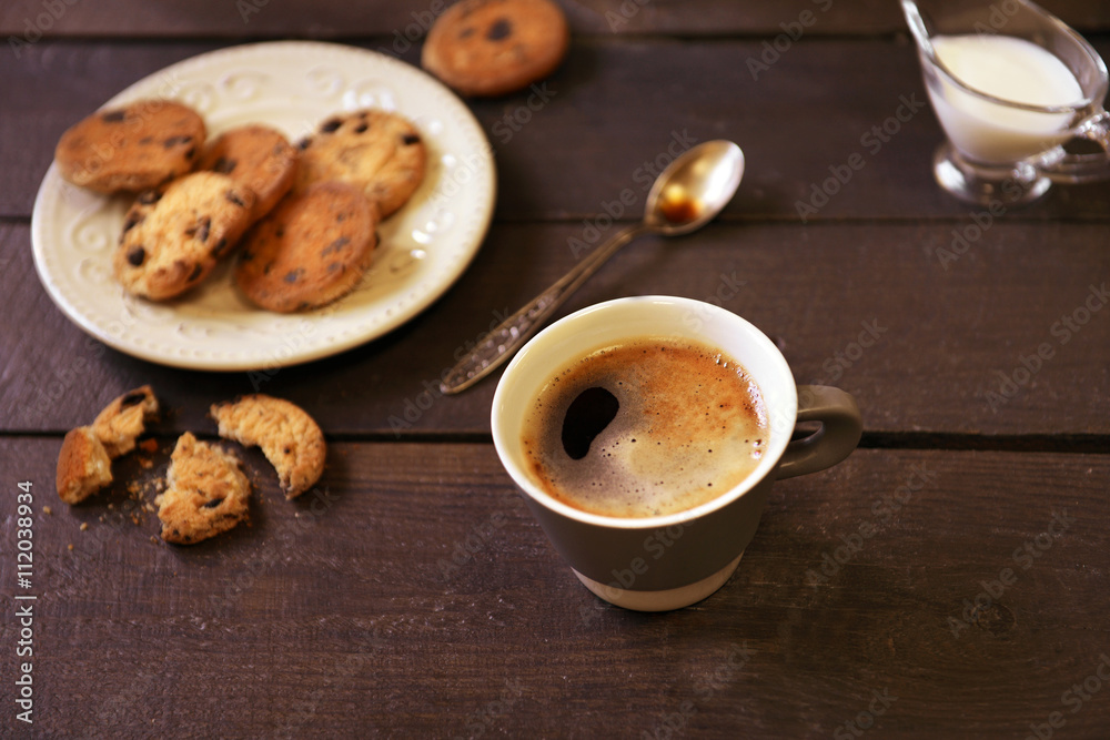 Cup of coffee with cookies on wooden table