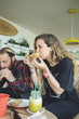 © Westend61 - Couple having breakfast in cafe, eating sandwiches and organic juices