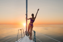Girl Standing On Yacht Bow. Lady On Yacht Raises Hand. Sunrise In The Caribbean Sea. Happier Than Ever.