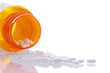 medication bottle on side with pills spilling out onto a reflective surface. Reflection of medication tablets on the table.