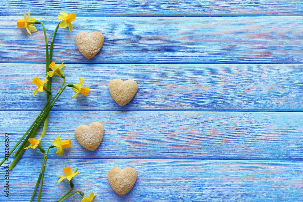 Yellow daffodils and biscuits on wooden background, closeup