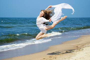 Wall Mural - Happy young girl jumping on the beach