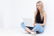 © MaxFrost - Happy young woman sitting on the floor and using laptop