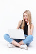 © MaxFrost - Happy young woman sitting on the floor and using laptop