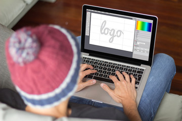 Fototapete - Young man on the sofa designing a logo