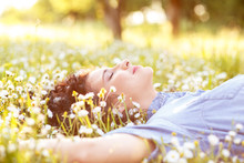 Beautiful Young Woman Laying On A Green Grass With White Flowers In A Park.