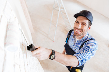 Close-up portrait of young handsome builder with paint roller