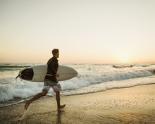 Caucasian Man Carrying Surfboard On Beach