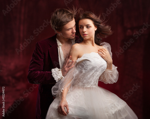 Fotografie, Obraz Beautiful man and woman dressed in medieval clothing stand in a room of the old abandoned castle