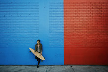 Caucasian Woman Holding Skateboard At Painted Wall